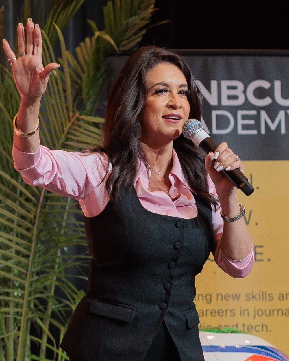 Dunia Elvir speaking with a microphone, one hand raised, at an NAHJ event